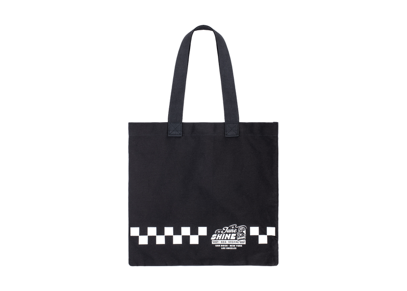 Black canvas tote bag with white checkerboard print and text that reads JuneShine, 1-866-99SHINE San Diego New York Los Angeles