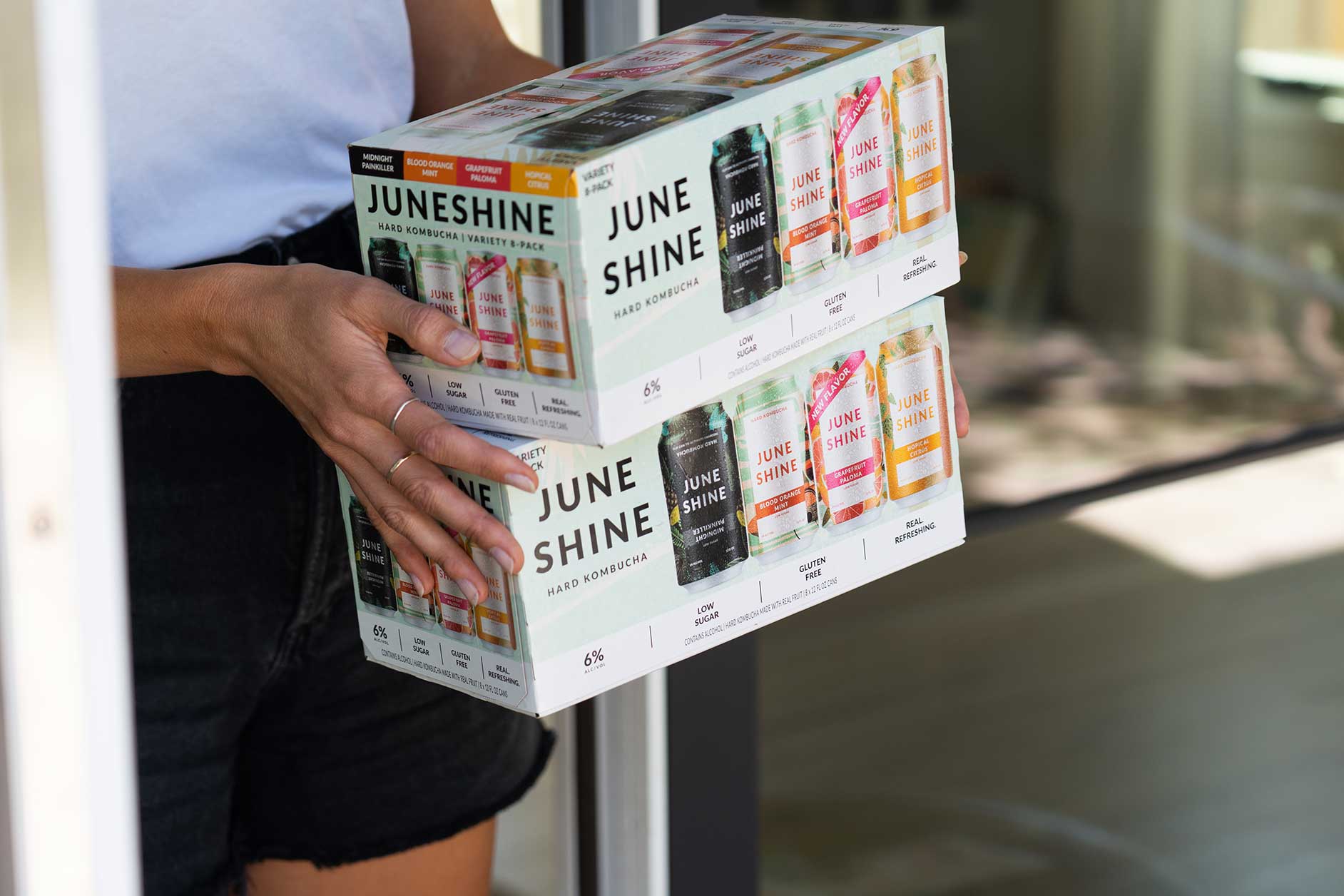 someone carrying JuneShine 6 packs