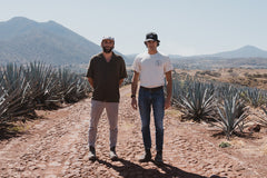 Forrest and Greg, cofounders, stand in the middle of an agave field in Mexico