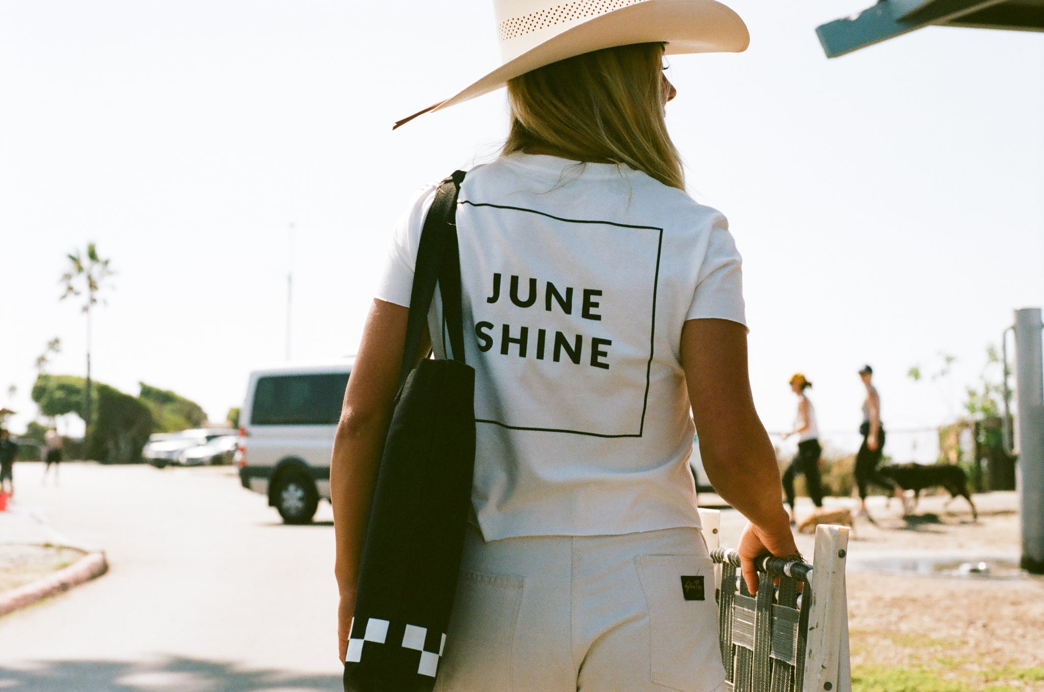 Girl wearing white juneshine tshirt and cowboy hat carrying the black juneshine tote bag
