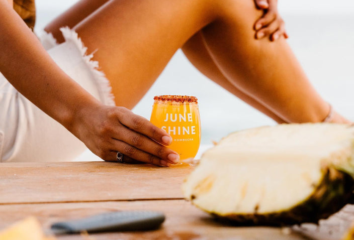 Woman holding a small glass of JuneShine with a tajin rim