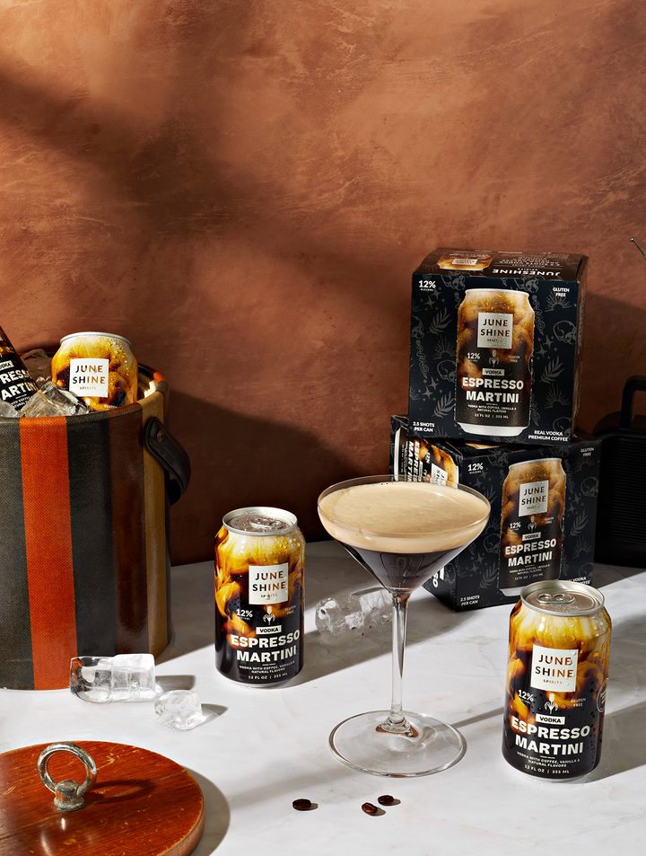 espresso martini cans and cartons with it poured into a glass with froth and coffee beans
