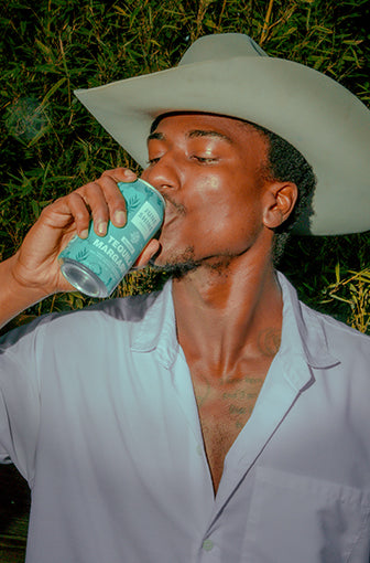 Man in cowboy hat drinking can of JuneShine Spirits Classic Tequila Margarita.