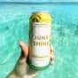 hand holding a JuneShine can in crystal clear tropical water